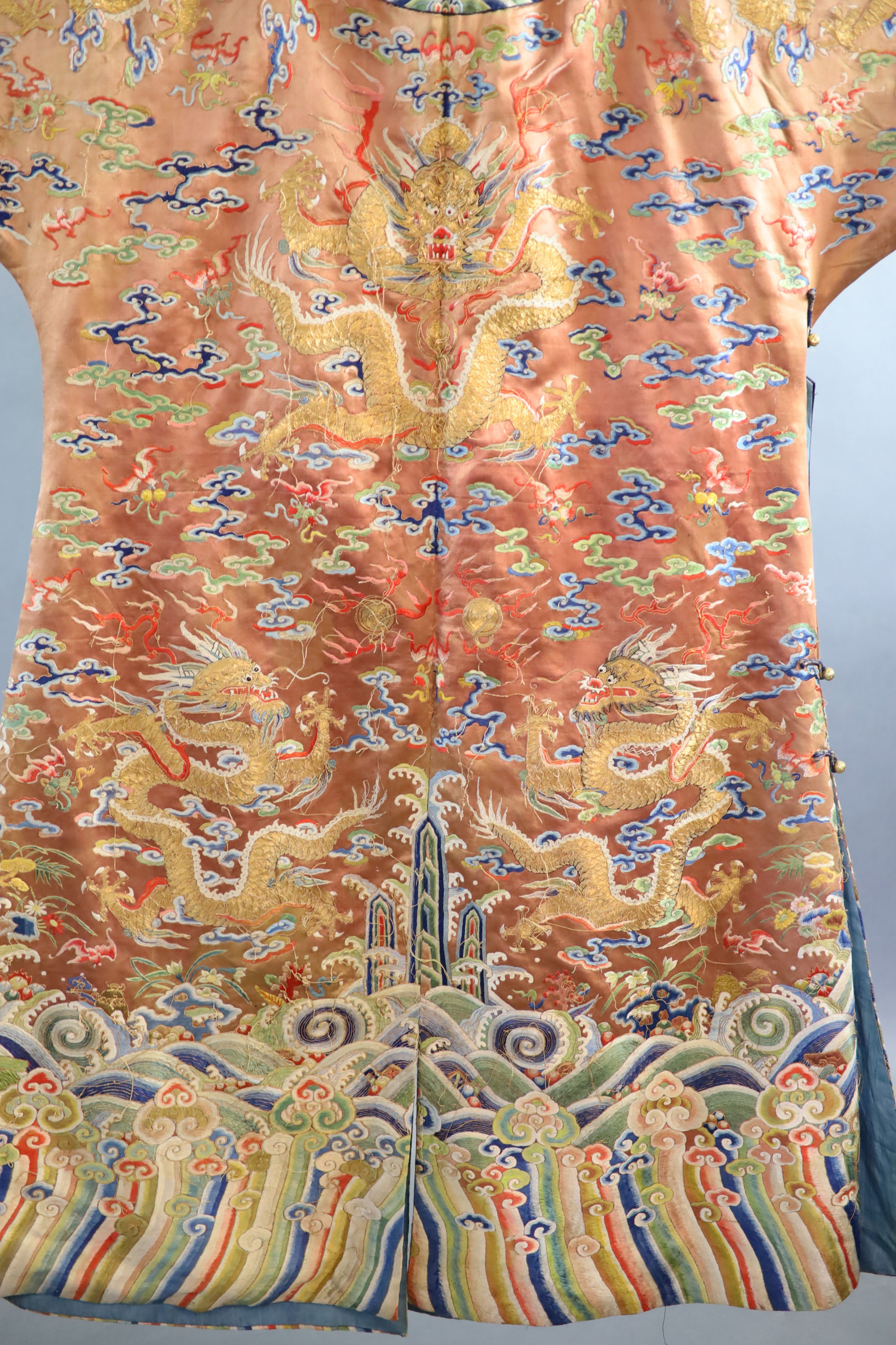 A Chinese apricot embroidered silk ‘dragon’ formal court robe, jifu, late Qing Dynasty, 131cm long, some alterations